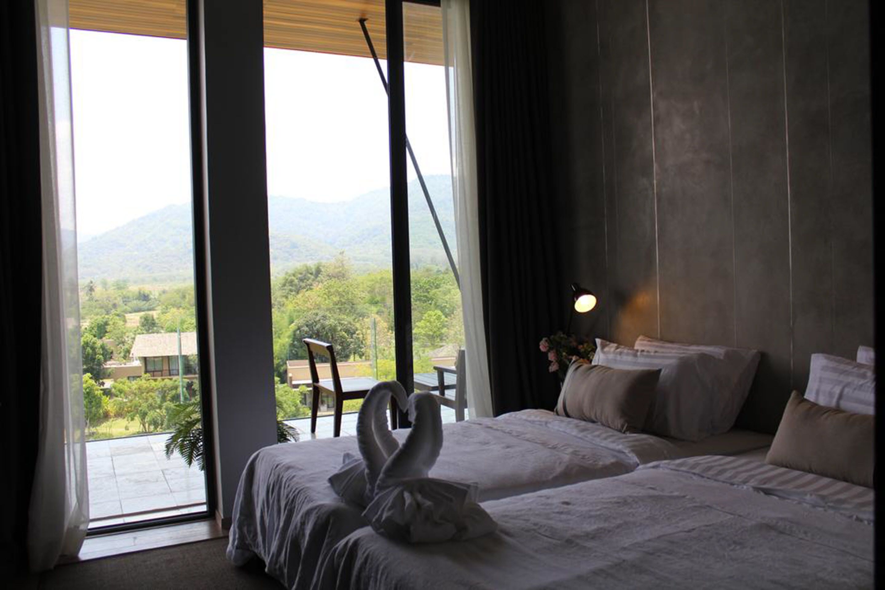 A hotel room with a bed, a chair, and a view of the outdoors.