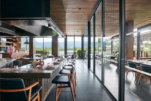 Un restaurant moderne doté d’un long bar, de hauts plafonds et de grandes fenêtres offrant une vue sur les montagnes.