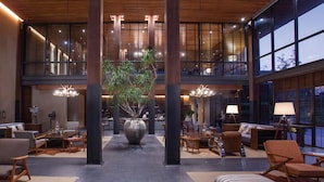 A spacious lobby with a central plant, seating areas, and large windows. - atta Lakeside Resort Suite (Pak Chong)
