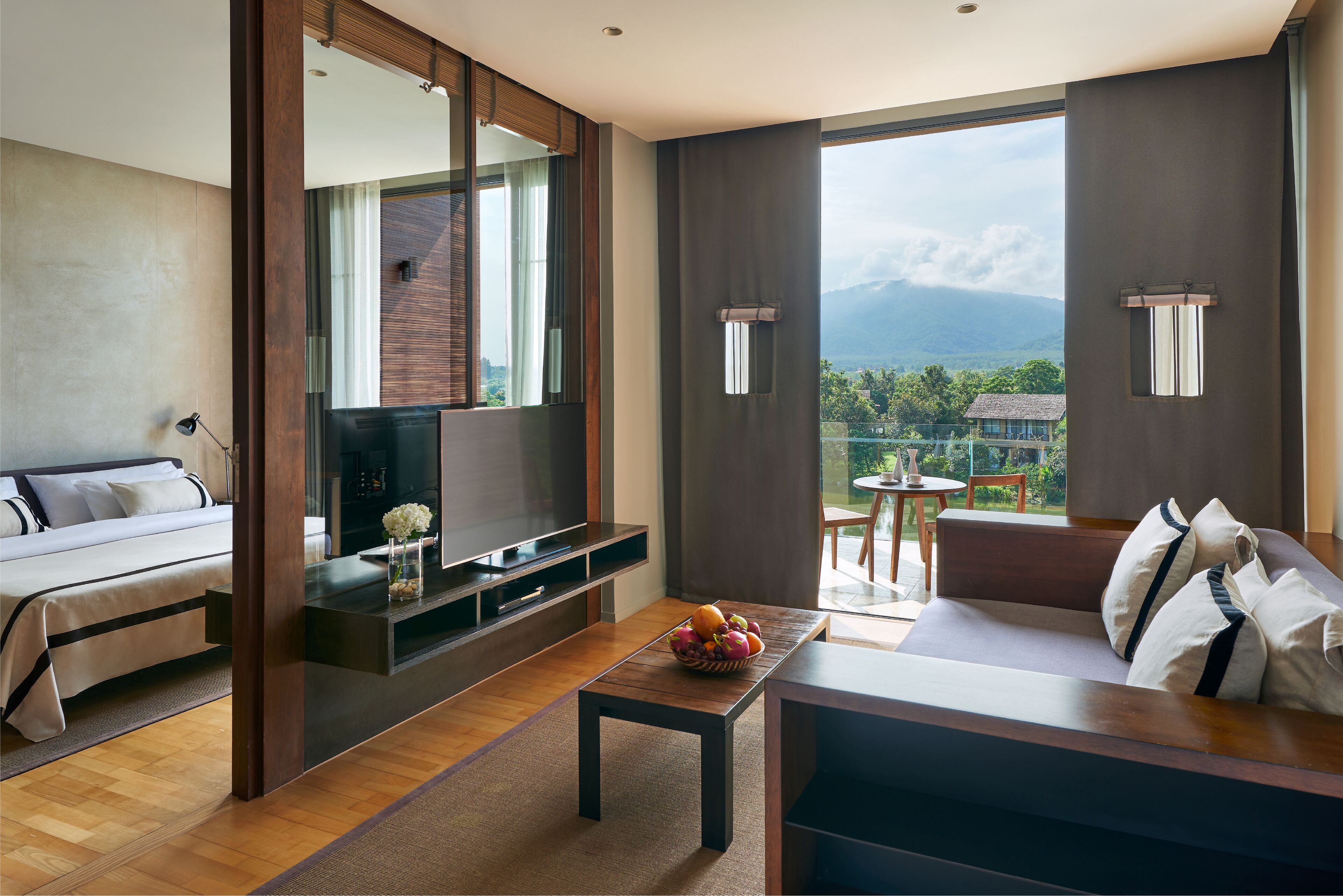 Ein modernes Hotelzimmer mit Bett, Fernseher, Essbereich und Bergblick.
