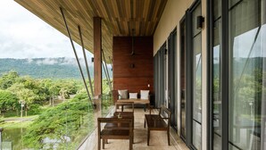 A balcony with a wooden ceiling, large windows, and a view of a lush landscape. - atta Lakeside Resort Suite (Pak Chong)