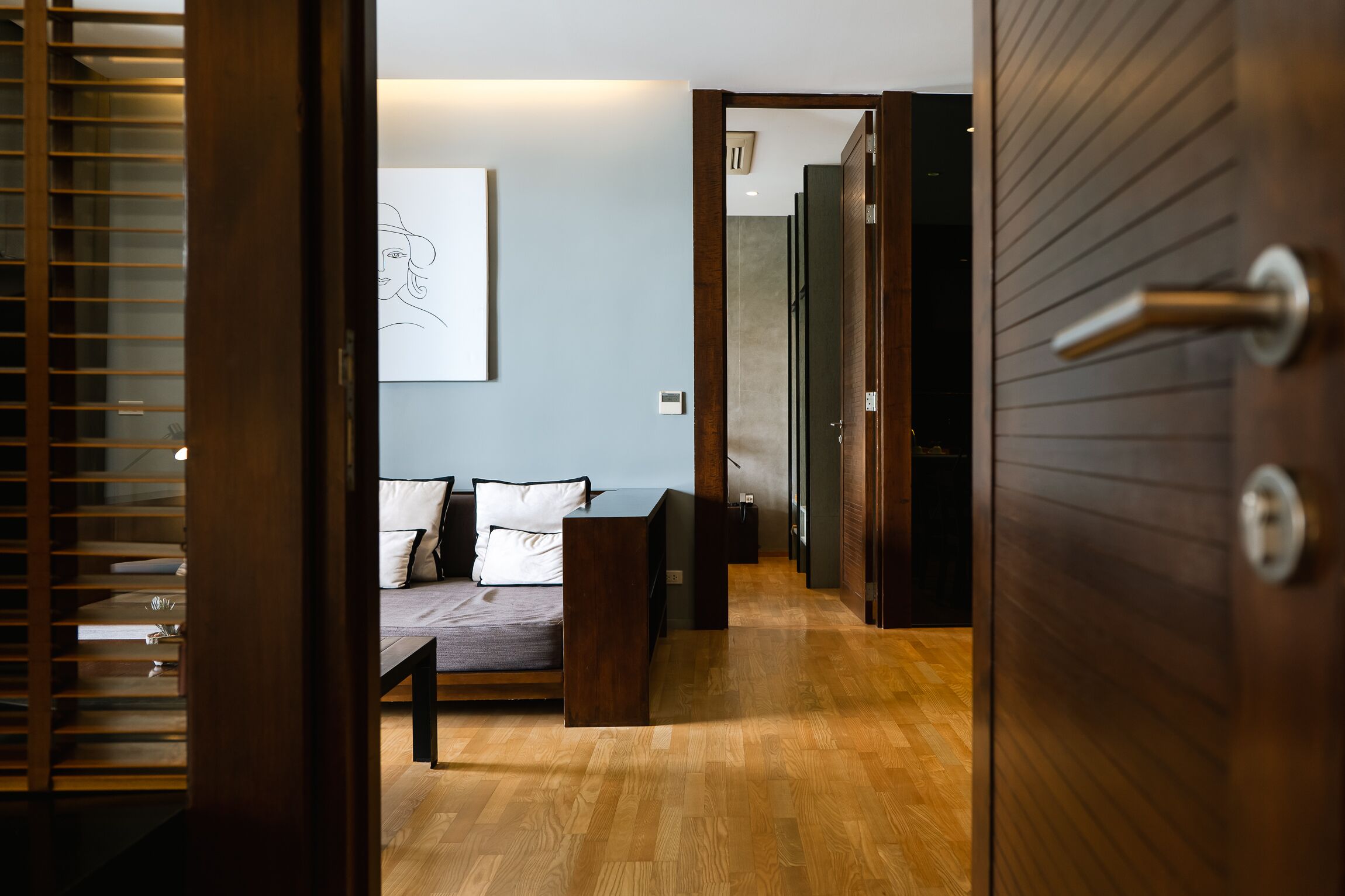 Ein modernes Schlafzimmer mit Holzboden, einem Bett mit weißer und schwarzer Bettwäsche, einem Nachttisch und einem an der Wand befestigten Kunstwerk.