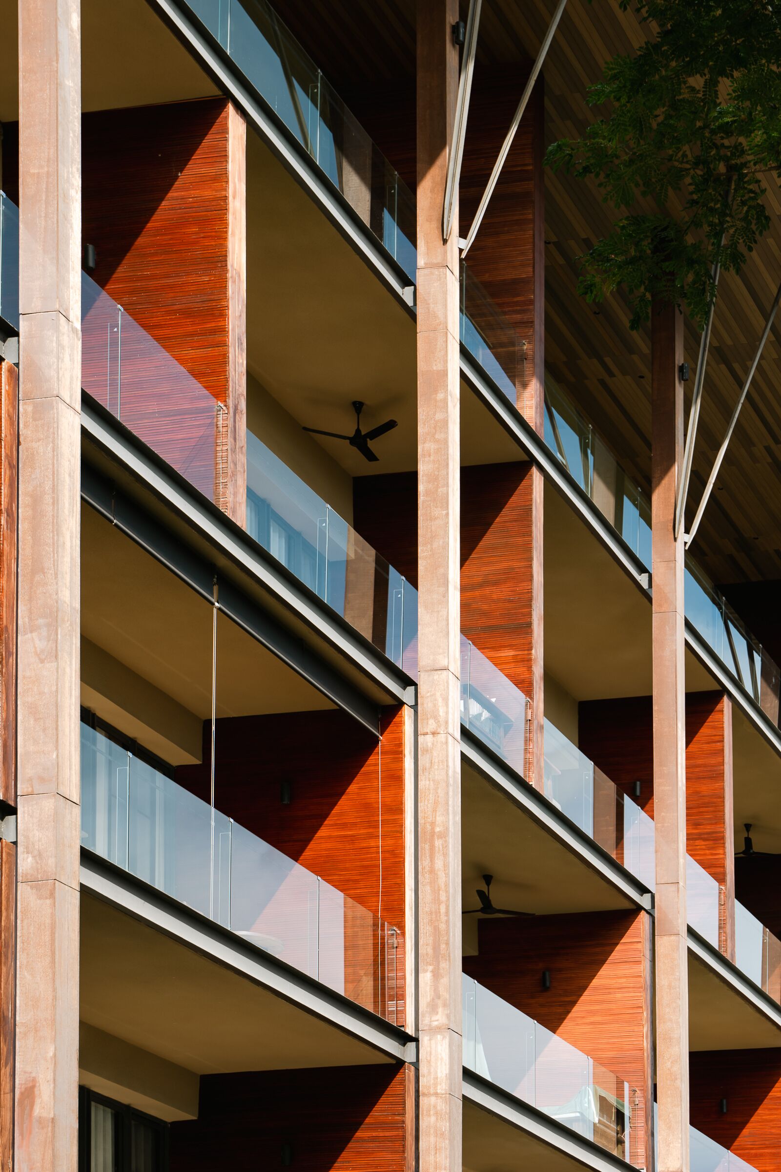 A multi-story building with a modern architectural design, featuring balconies with glass railings and wooden accents.