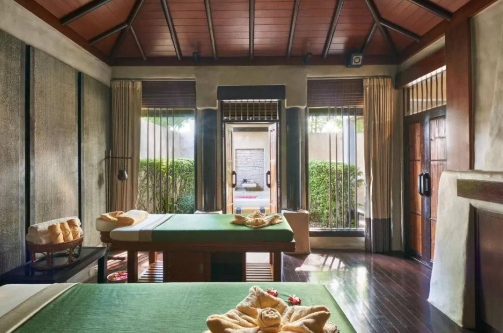 Ein Zimmer mit Massagetisch, einem kleinen Tisch mit Brot und Blick auf einen Garten durch eine Tür.