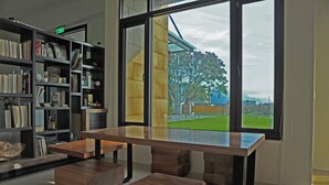 A modern library with a large wooden table and bookshelves filled with books and decorative items. - Psminshuku (Ji'an)