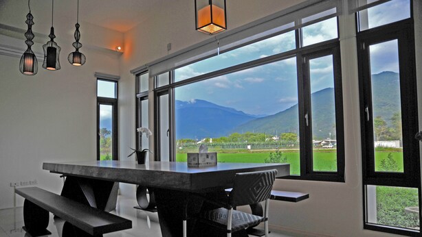 A modern dining area with a large table, benches, and large windows offering a view of mountains and greenery. - Psminshuku (Ji'an)