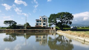 A modern two-story house with a large tree in front, reflecting in a calm body of water. - Psminshuku (Ji'an)