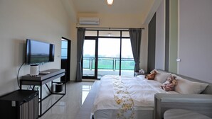 A hotel room with a bed, a TV, a desk, and a balcony with curtains. - Psminshuku (Ji'an)