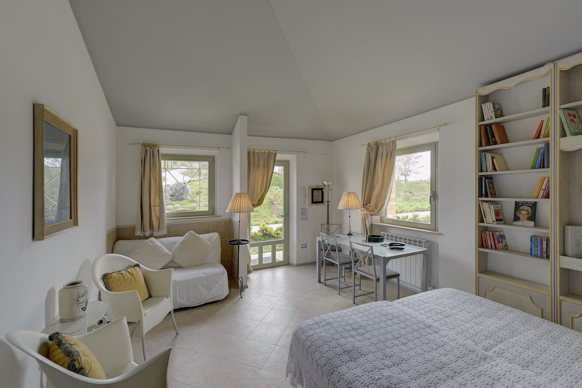 A bedroom with a bed, a desk, a chair, a sofa, and a bookshelf.