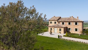 A two-story stone house with a tiled roof, surrounded by a well-maintained lawn and trees. - Relais Il Margarito (Montefano)