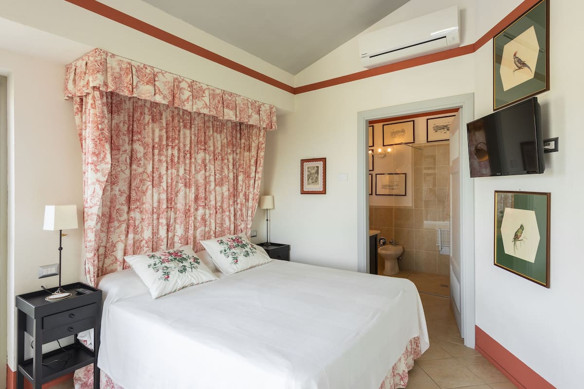 A neatly arranged bedroom with a bed, nightstands, and a bathroom visible through an open door.