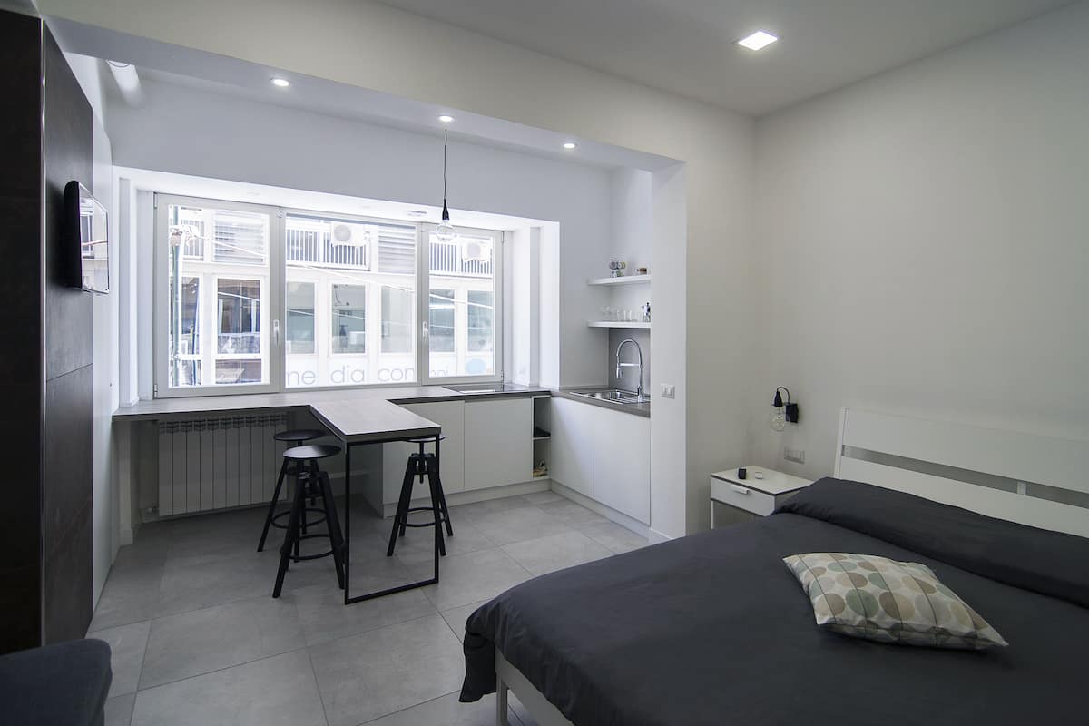A modern bedroom with a bed, a desk, and a window.