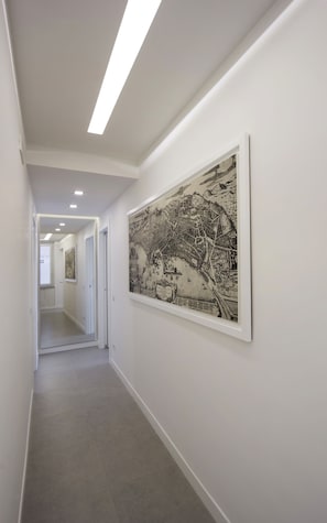 Un pasillo con un gran mural en blanco y negro de un mapa en la pared, paredes blancas y piso de baldosas.