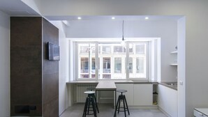 Een kleine keuken met een eethoek, een raam met zonwering en een inbouwoven.