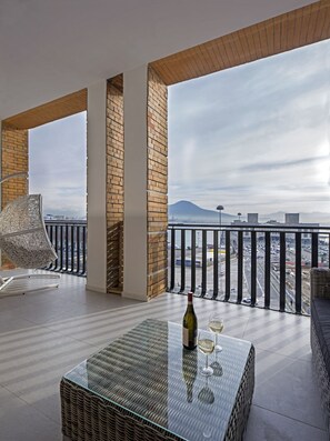 A balcony with a wicker table, a bottle of wine, and two glasses. - Relais Castel Nuovo (Naples)