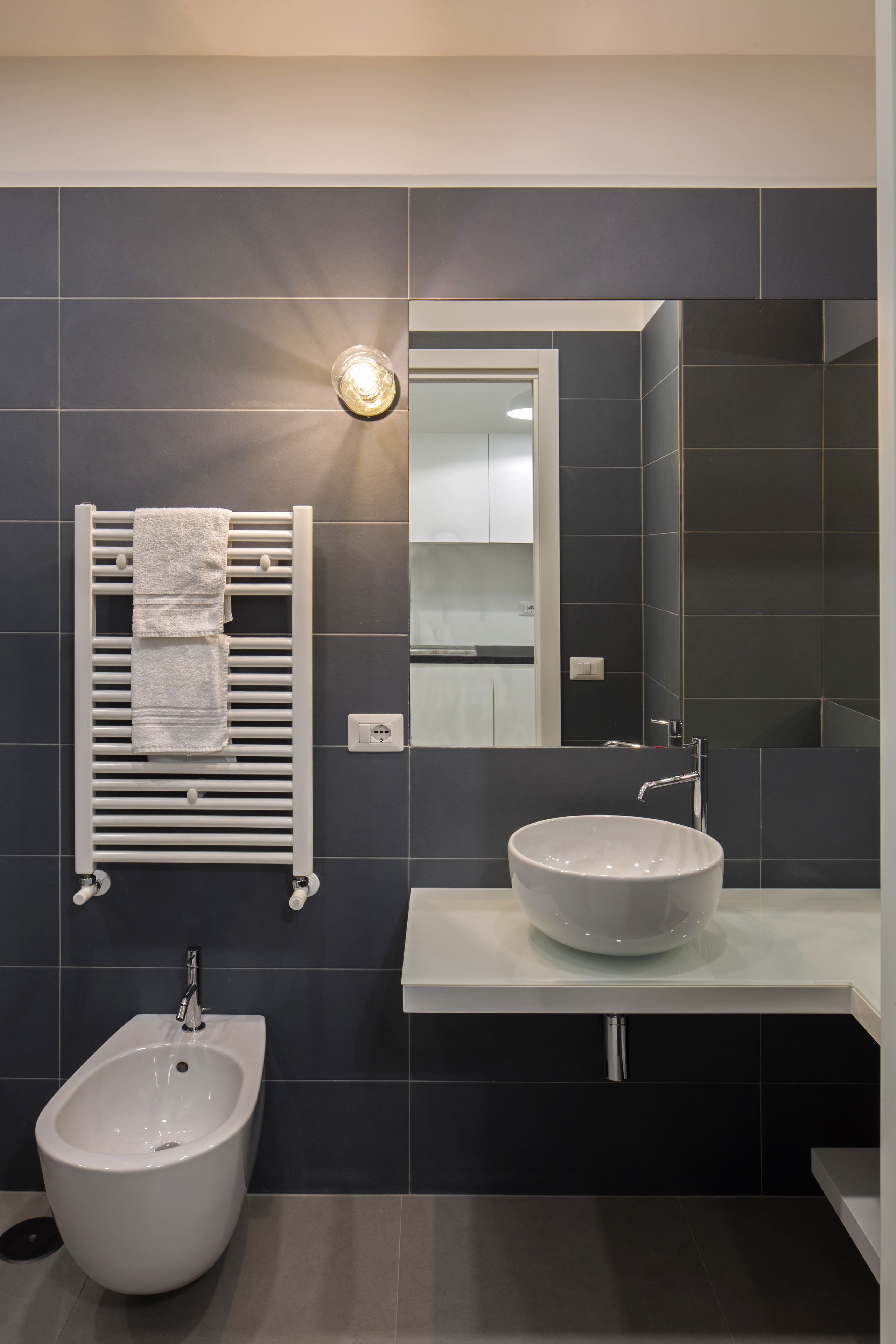 A modern bathroom with a bidet, a large mirror, and a white sink.