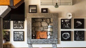 Un comedor rústico con chimenea de piedra, vigas de madera y suelo a cuadros.