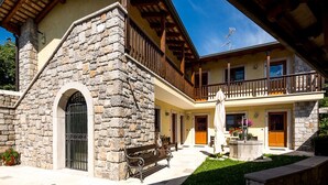 Un edificio de piedra con un balcón, una escalera de madera y un banco.