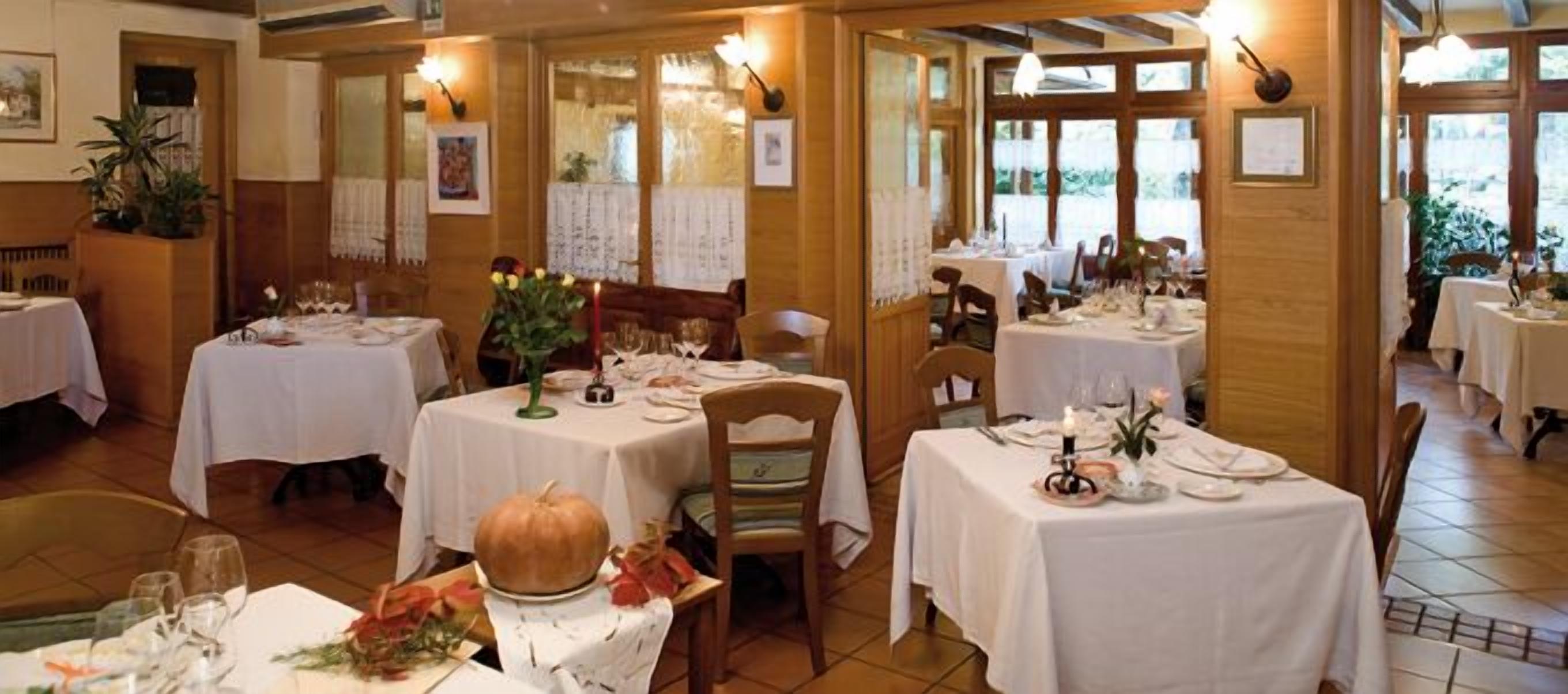 Ein Restaurant mit mehreren gedeckten Tischen, mit weißen Tischdecken und Kerzen.