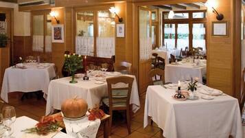 Ein Restaurant mit mehreren gedeckten Tischen, mit weißen Tischdecken und Kerzen.