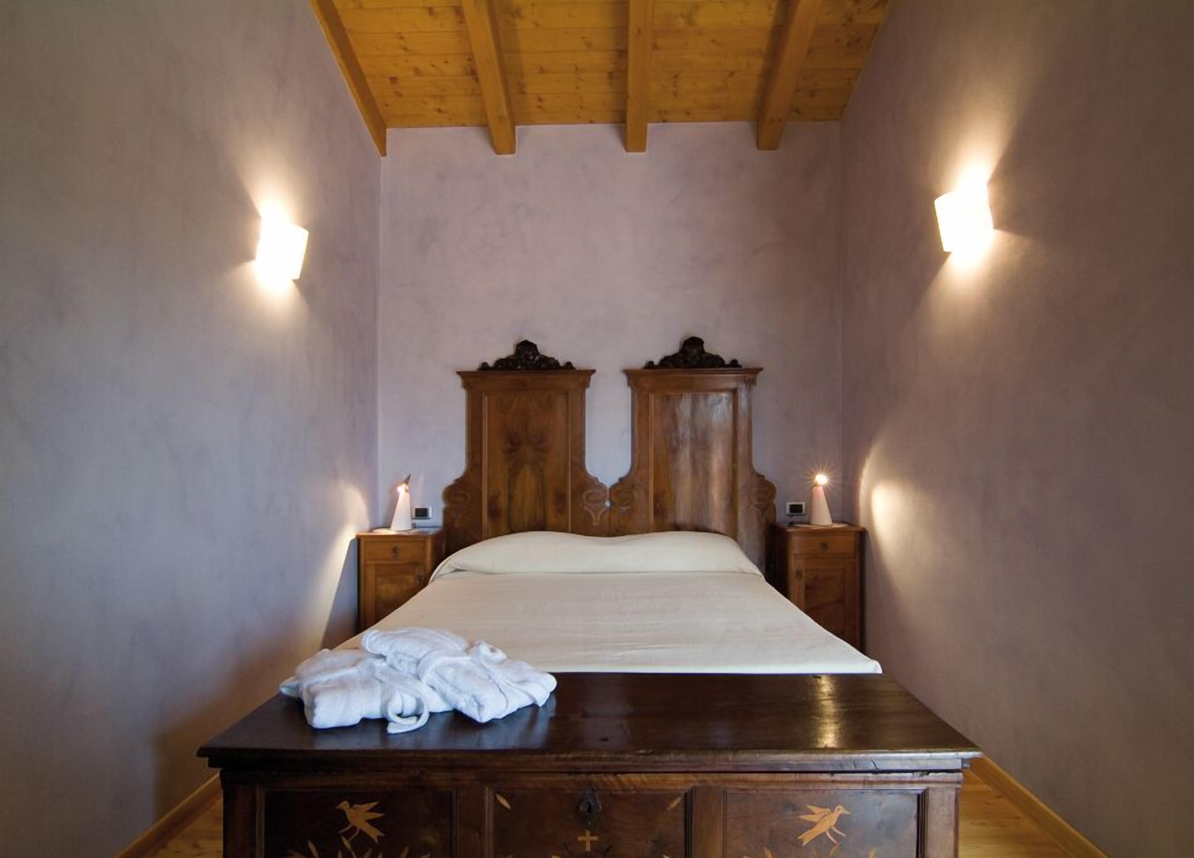 Una camera da letto con un letto di legno, due comodini e un comò in legno con degli asciugamani sopra.
