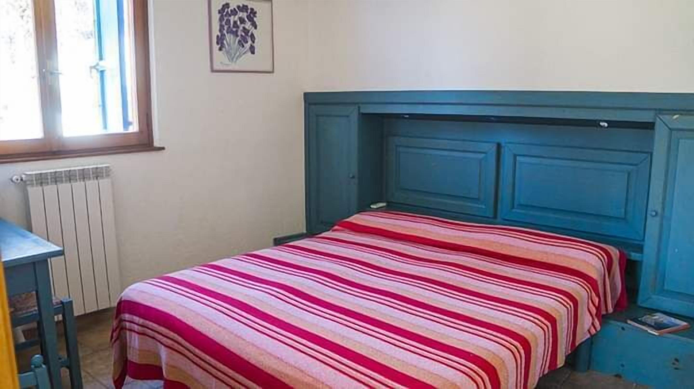 Un dormitorio con cama, un radiador, una ventana y una puerta.