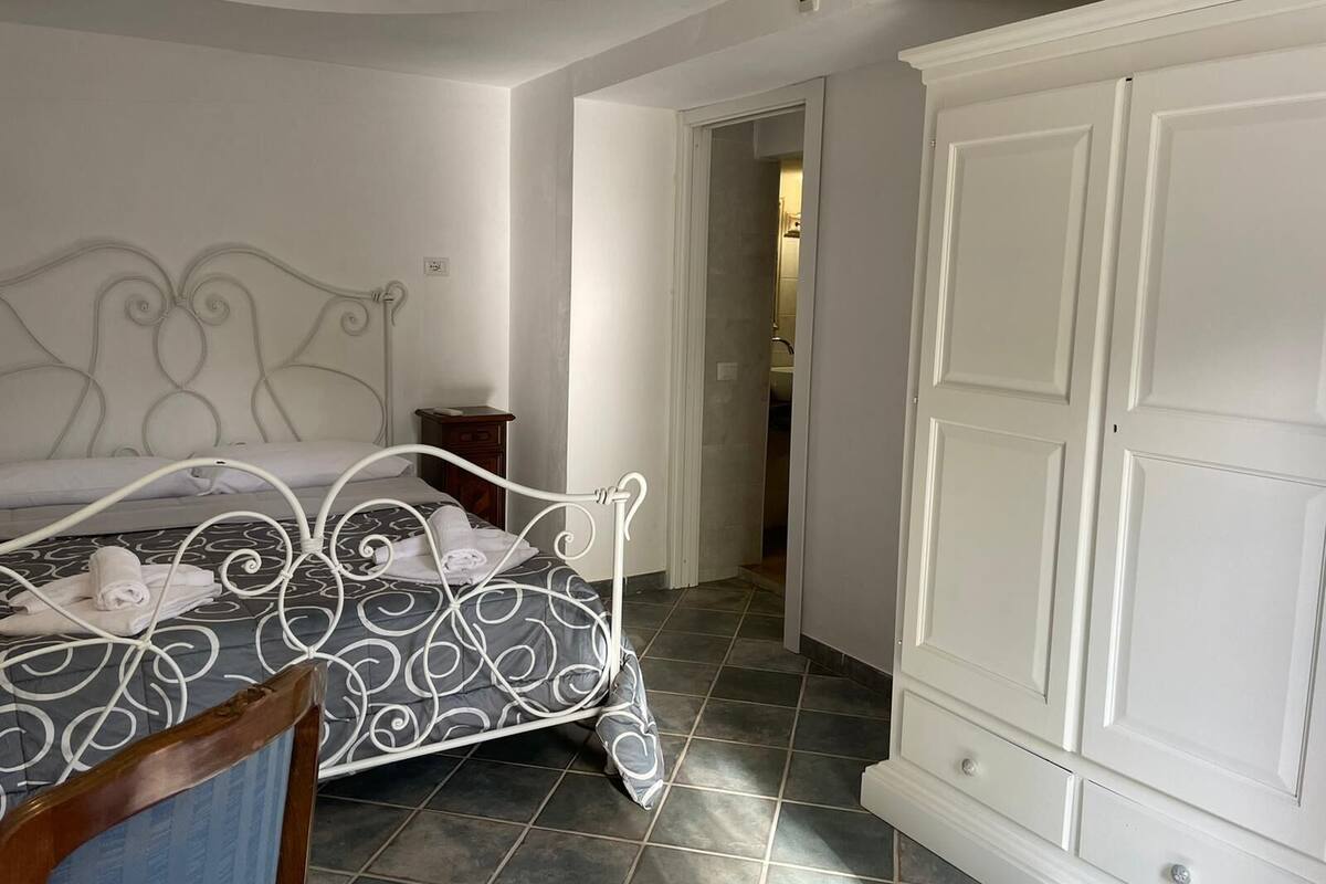 A bedroom with a bed, a wardrobe, and a bathroom visible through an open door.