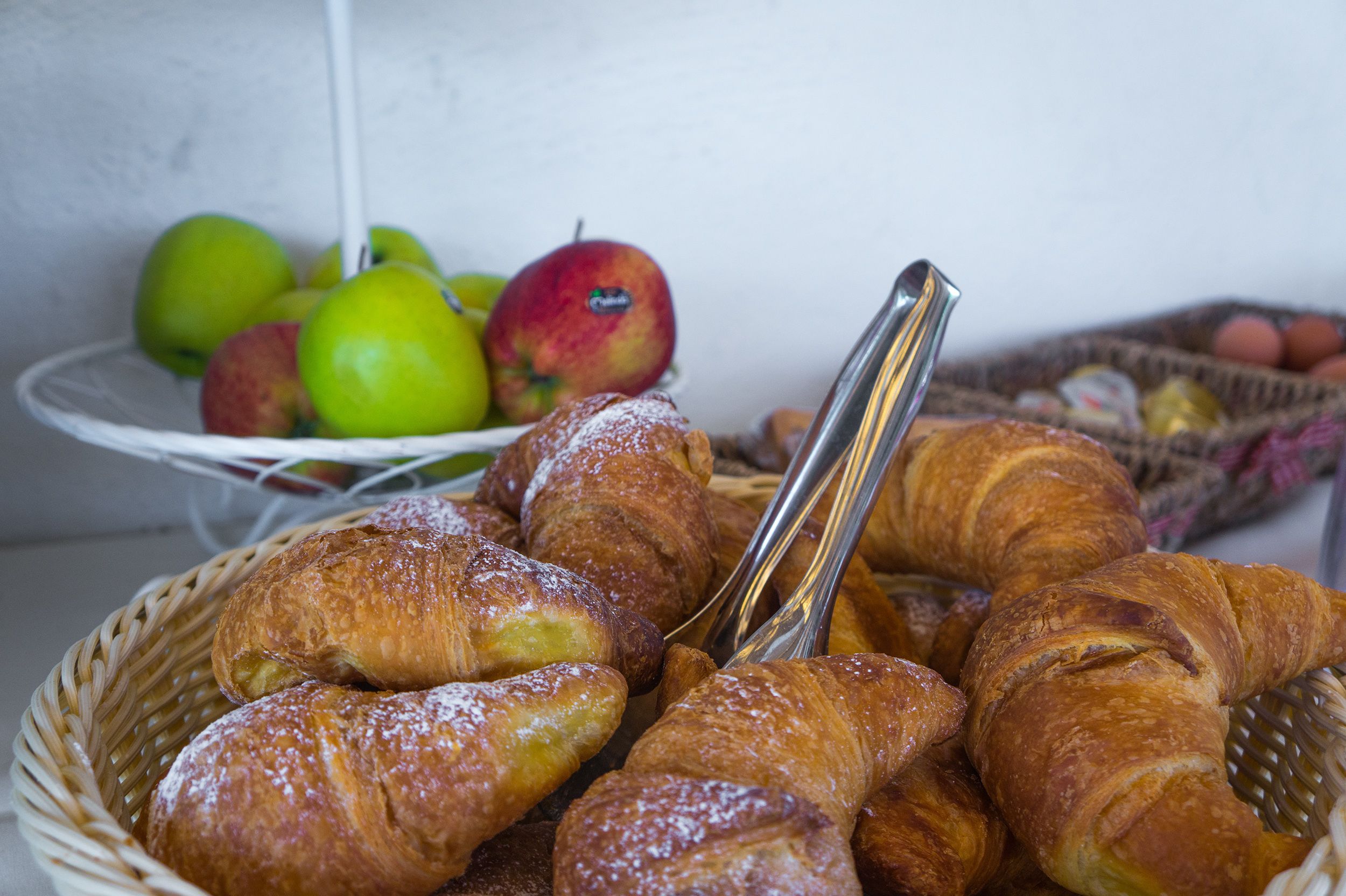 Un cesto con croissant e mele.