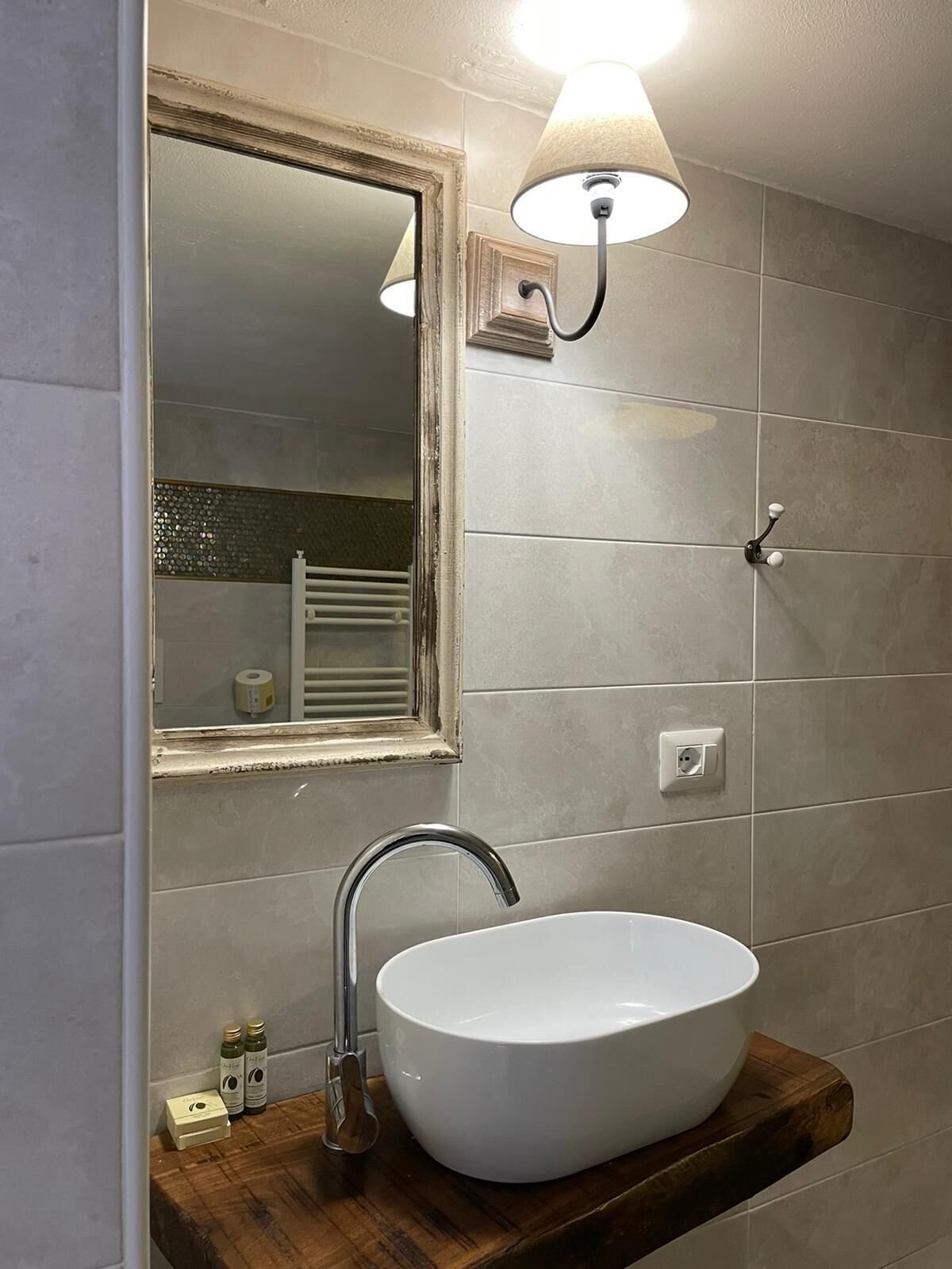 A bathroom with a white sink, a mirror, and a wall-mounted light fixture.
