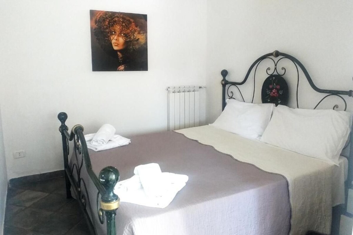 A bedroom with a bed, a radiator, and a painting on the wall.