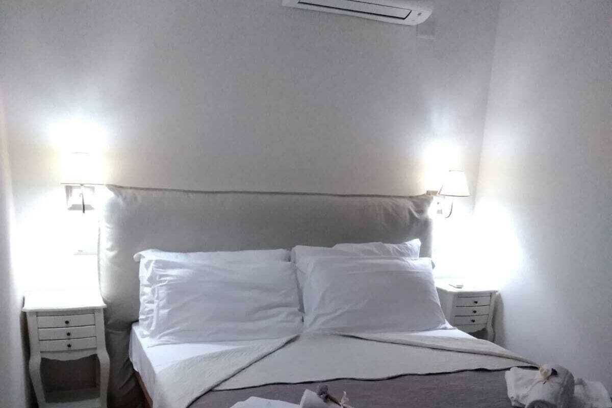 A neatly made bed with white linens, two bedside tables with lamps, and a small chair.