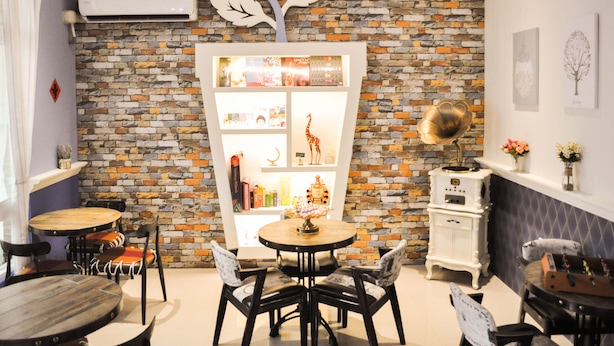 Un comedor acogedor con una pared de ladrillo, un armario blanco con puertas de cristal y una estufa antigua.