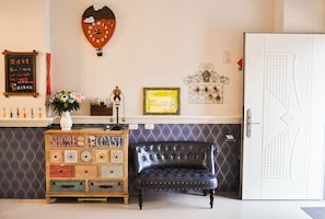 A room with a wooden dresser labeled "SHORES COAST," a black leather chair, a wall clock, and a door with a geometric pattern. - Sun Giraffe Taitung B&B (Taitung)