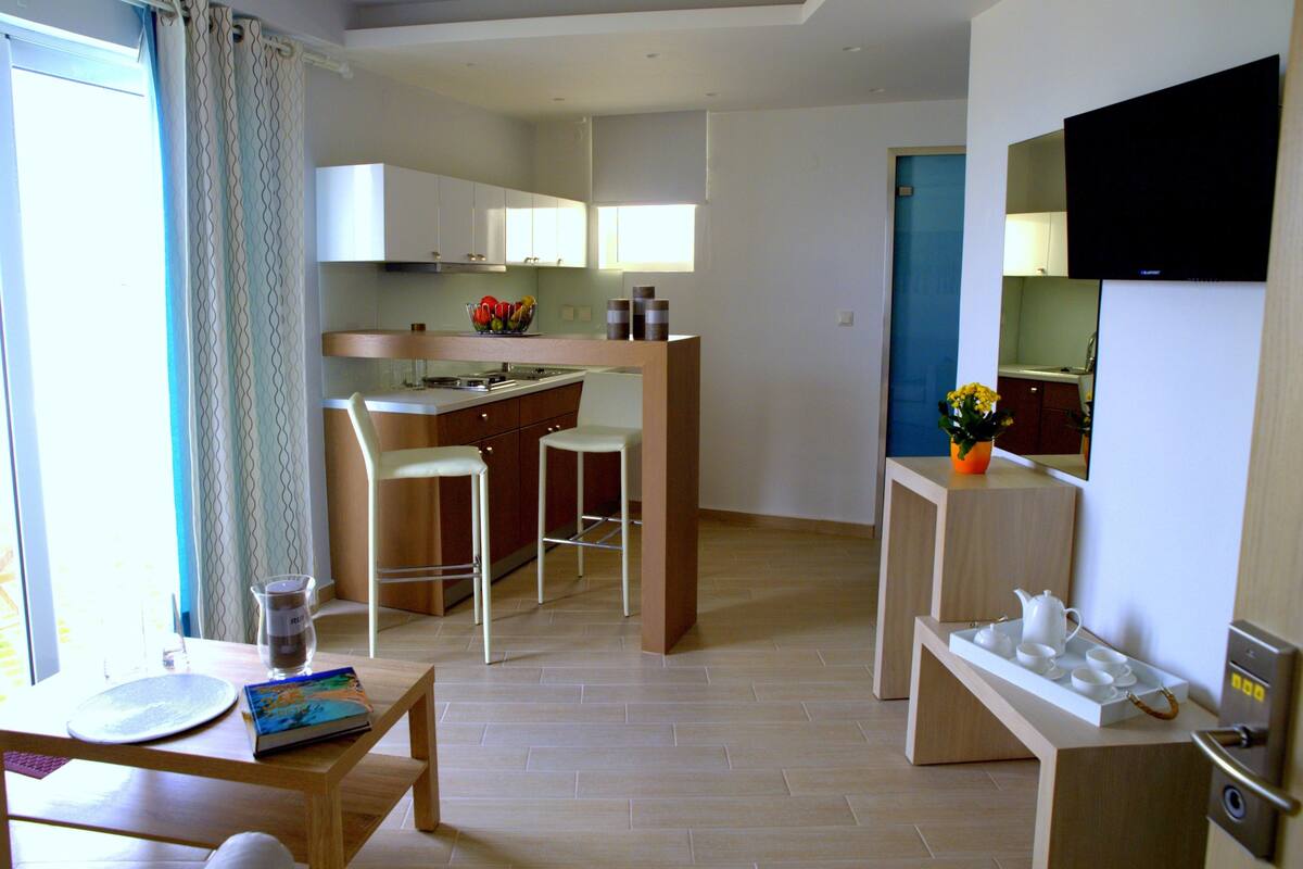 A compact kitchen with a dining area, a small bar, and a bathroom visible through a door.
