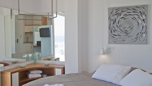 Habitación de hotel moderna con cama, un espejo grande, televisor y vista al mar.