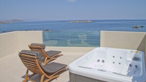 Un balcón con hidromasaje y dos sillones de descanso con vistas al mar azul y transparente.