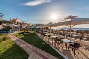 Enjoy al fresco dining on the hotel's scenic waterfront terrace, surrounded by tables and chairs.