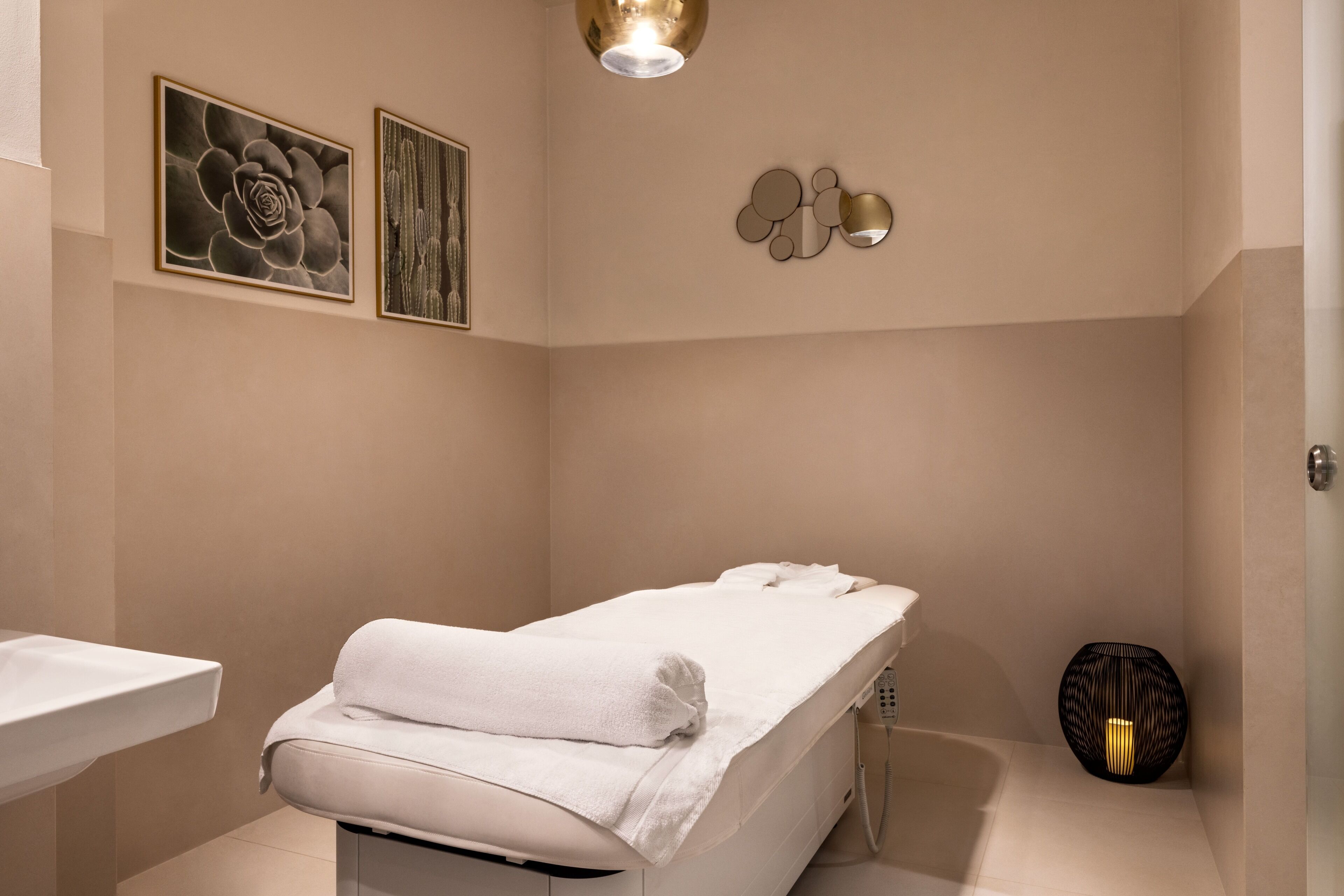 A modern bathroom with a white bathtub, a sink, and two framed artworks on the wall.