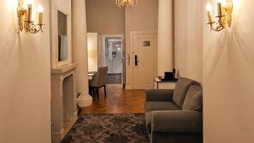 A hallway with a sofa, a chandelier, and wall sconces.