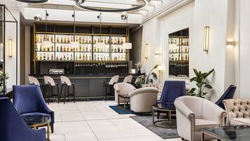A bar area with a variety of liquor bottles, bar stools, and a seating area with armchairs and a sofa.