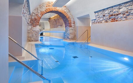 An indoor swimming pool with a stone archway and a glass railing.
