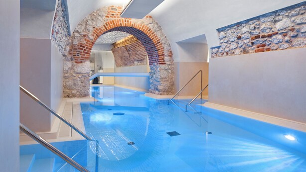 An indoor swimming pool with a stone archway and a glass railing.