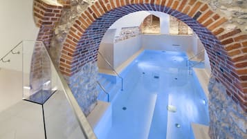 A spa area with a brick archway, a glass railing, and a blue-tiled floor.