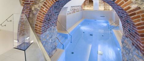 A spa area with a brick archway, a glass railing, and a blue-tiled floor.