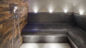Ducha en esquina con pared y piso cubiertos de azulejos, un cabezal de ducha y una perilla de control.