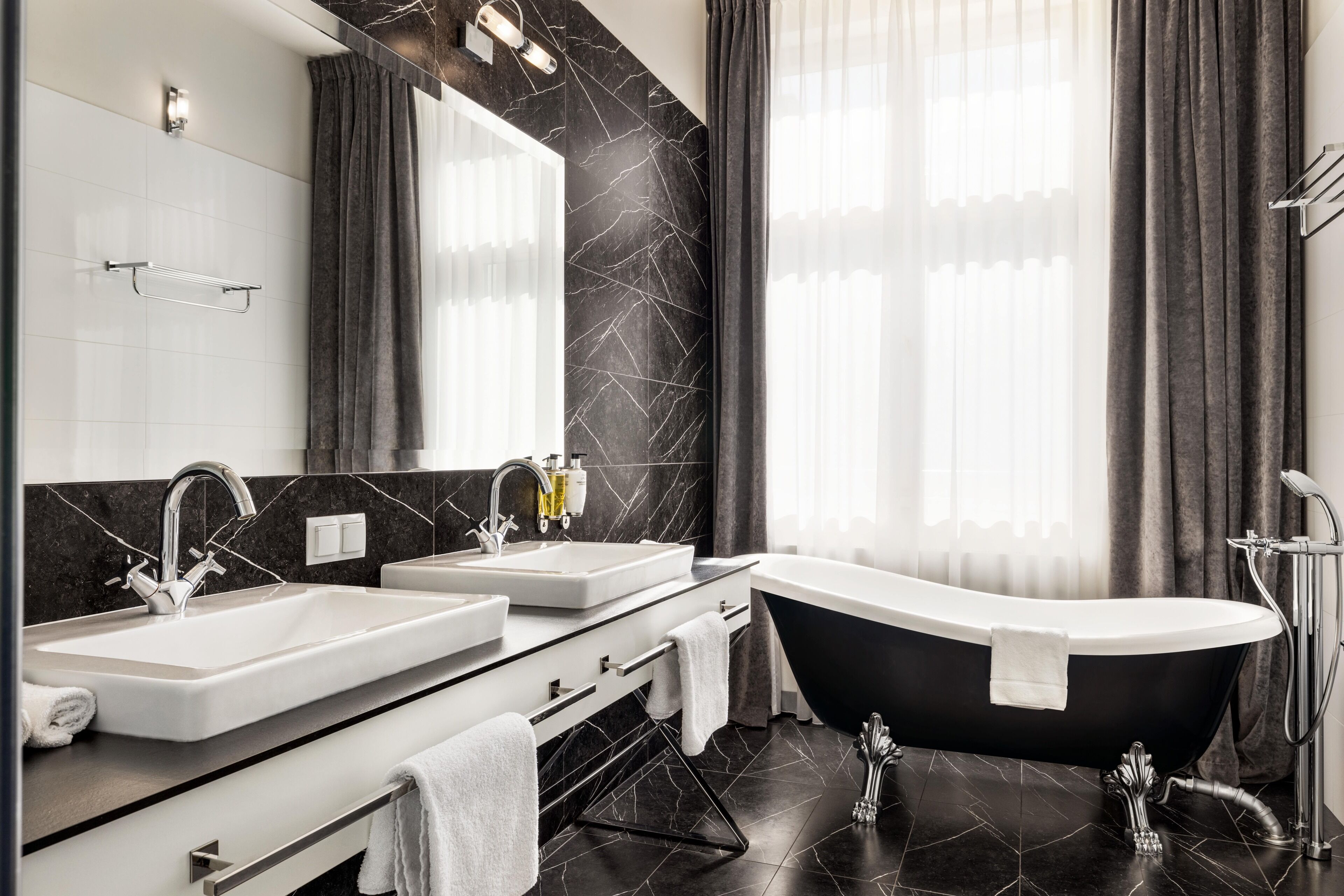 A modern bathroom with a freestanding bathtub, two sinks, a vanity, and a large mirror.