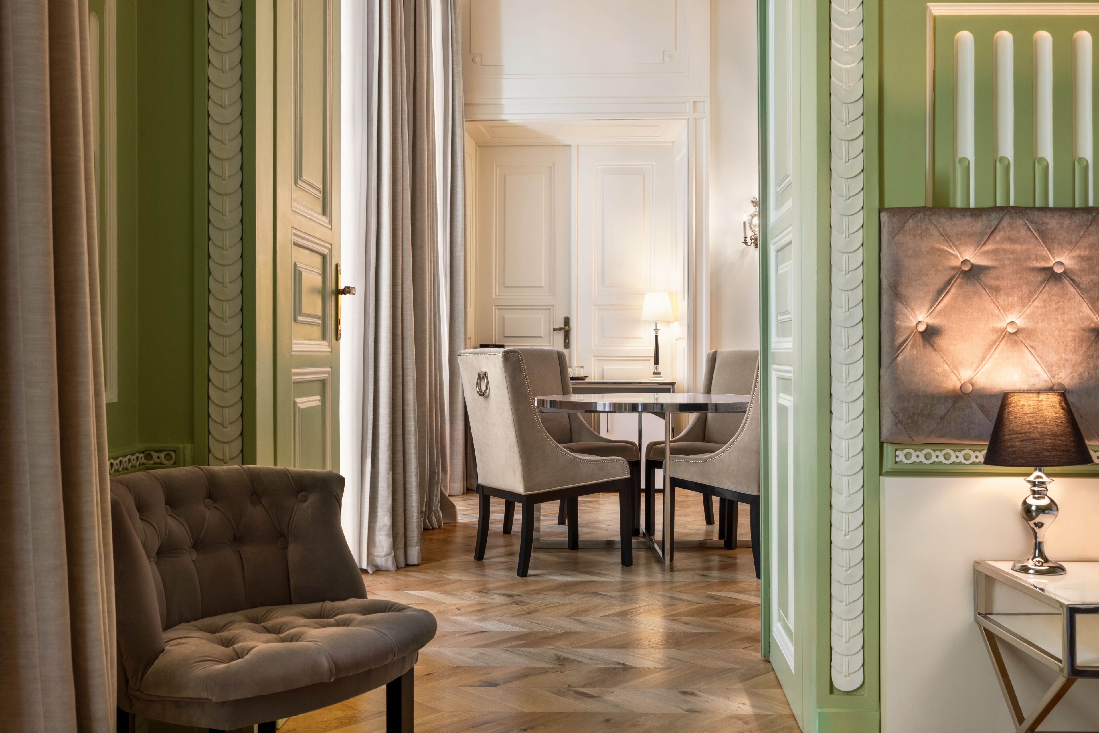 Een kamer met een gestuikte bank, een eettafel met stoelen en een wand met decoratieve panelen.