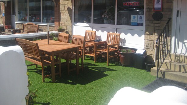 An outdoor seating area with wooden tables and chairs, a sign for The Mornington Hotel, and a visible entrance to the building. - The Mornington Hotel (Blackpool)
