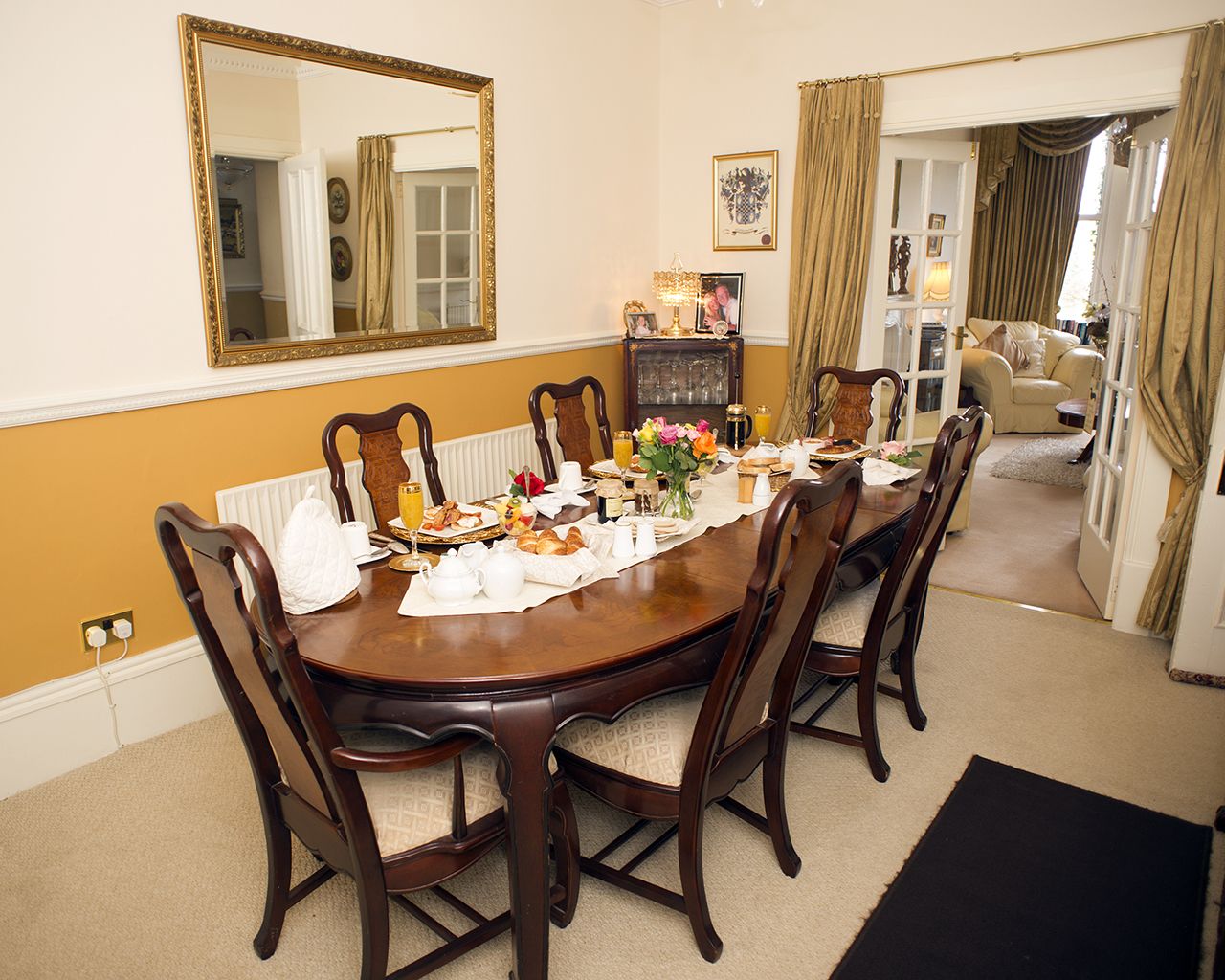 A dining room with a large wooden table set for breakfast, surrounded by chairs.