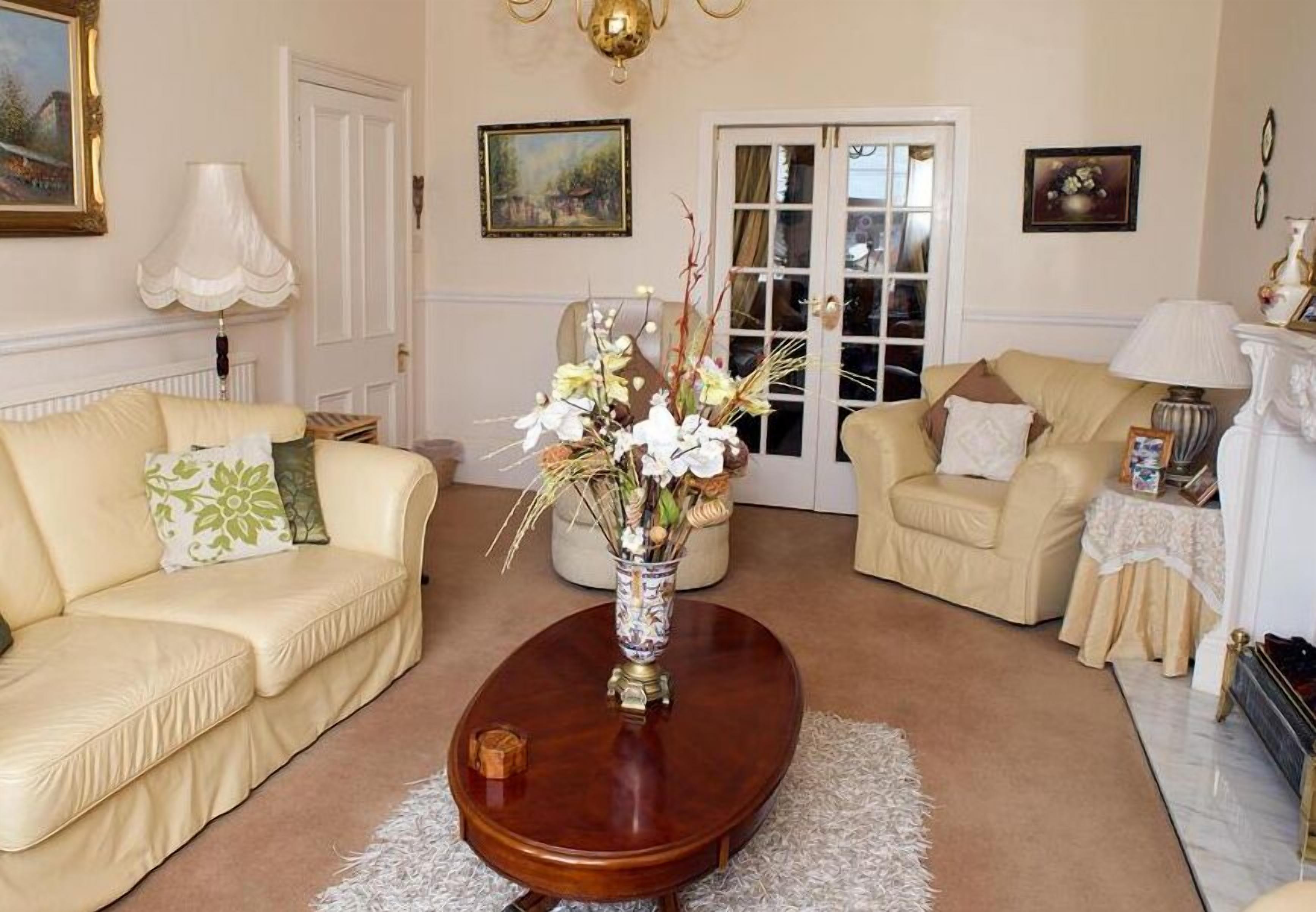 A living room with two cream-colored sofas, a wooden coffee table, and a vase with flowers.